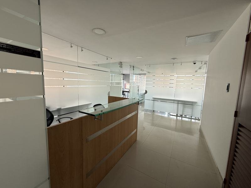 Recepción del piso 7 con mueble de recepción y divisiones en vidrio