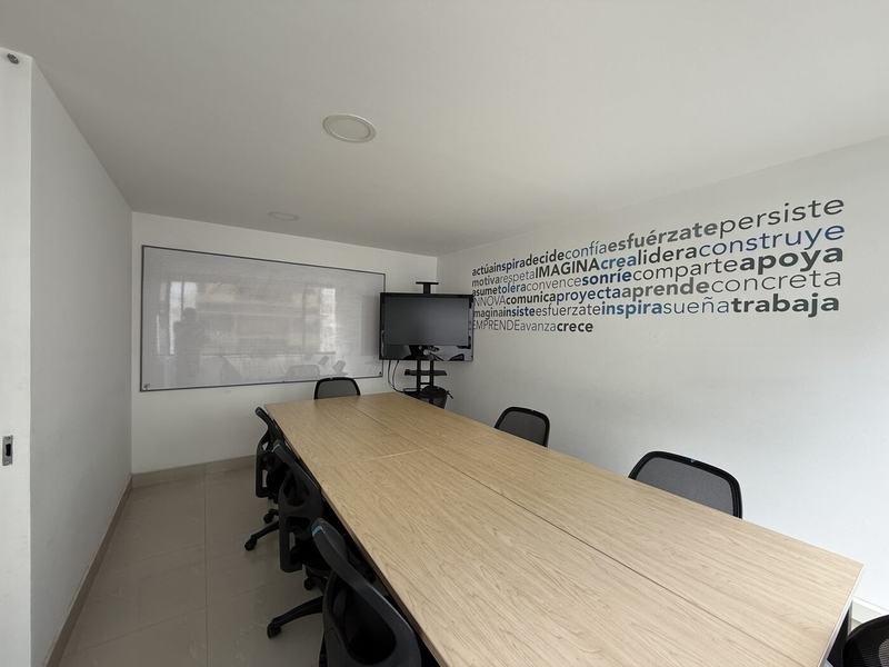 Sala de juntas amoblada con mesa para 8 personas y televisor